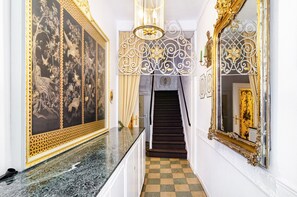 Eine prachtvolle Eingangshalle mit Marmorboden, aufwendigen Wandverzierungen, einer Treppe und einem großen Spiegel.