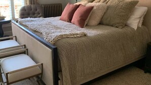 Une chambre à coucher avec un lit, une table de chevet, une chaise et une fenêtre avec des rideaux.