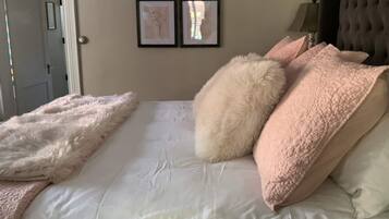 A bedroom with a bed, pillows, a door, and wall art.