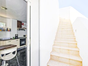 Una cocina moderna con horno empotrado, cafetera y comedor con mesa y sillas blancas.