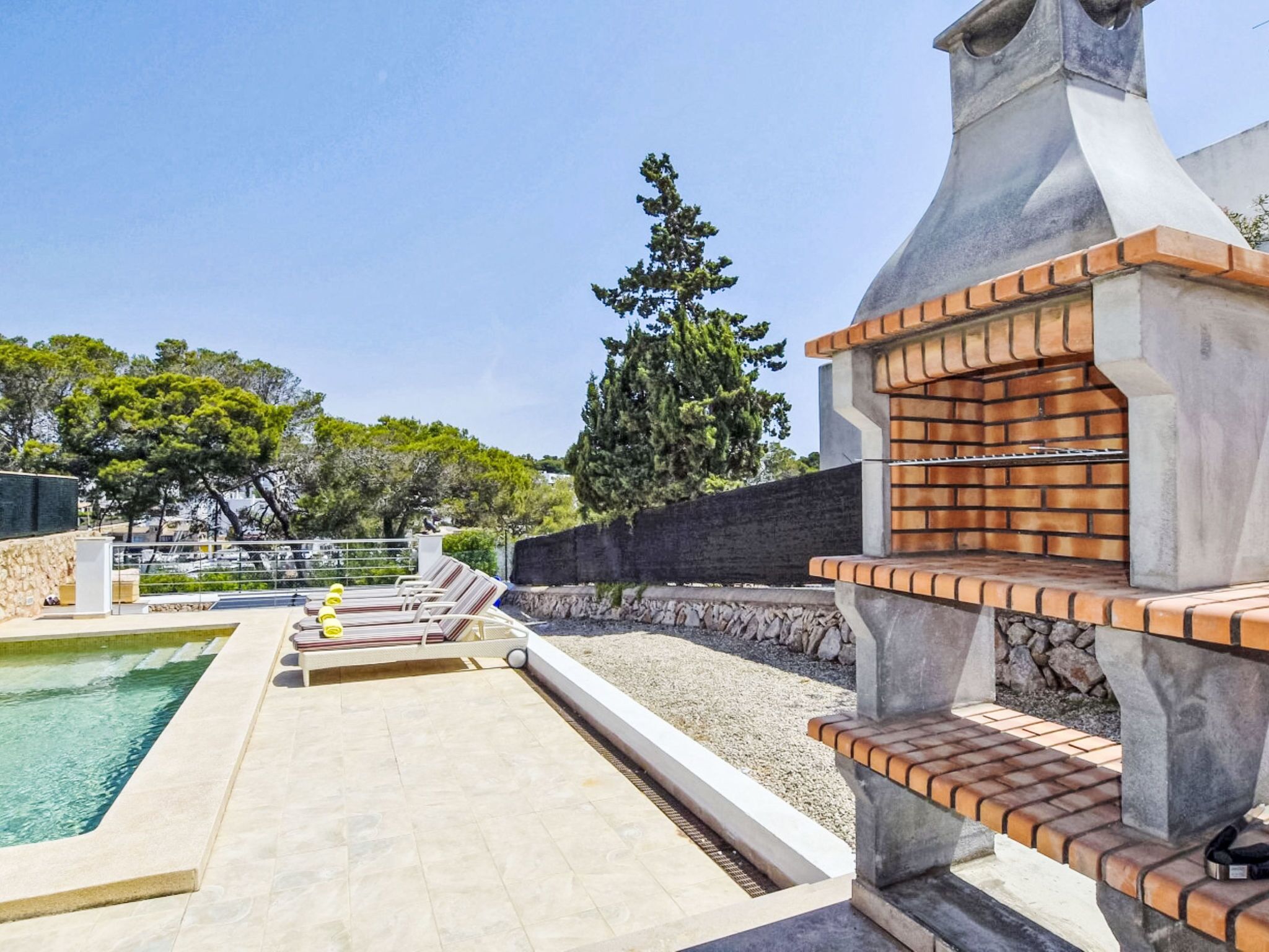 A pool area with lounge chairs and a barbecue grill.