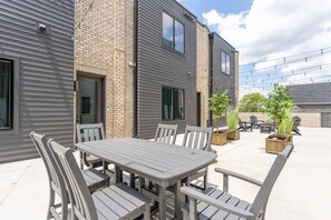 Un patio con mesa y sillas, un muro de ladrillo y una terraza de madera.