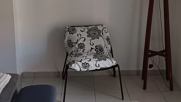 Et værelse med en hvid sofa, en blå bænk, en stjerneformet stol, en rød gulvlampe og en lurvet måtte.