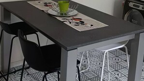 Et spisebord med stole, en grøn kop og en dekorativ dug.