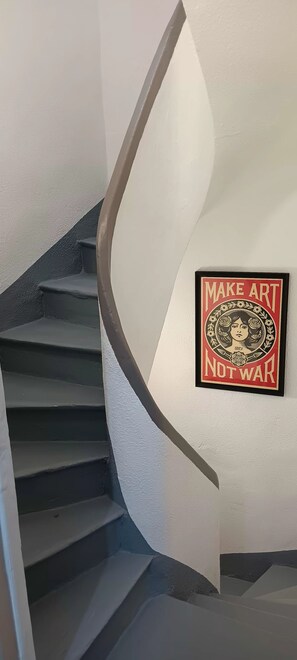 Eine Treppe mit Handlauf und einem an der Wand befestigten Schild, auf dem 'MAKE ART NOT WAR' steht.