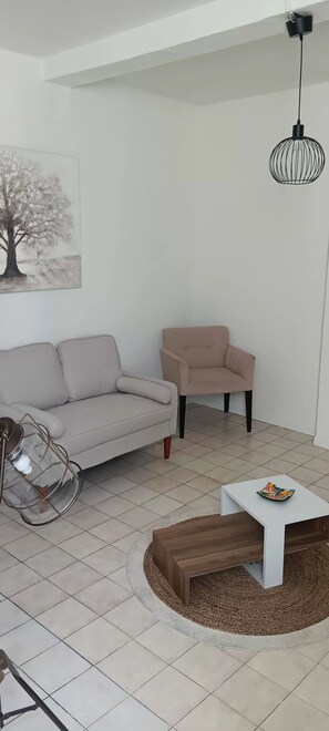 Ein Wohnzimmer mit einer Couch, einem Sessel, einem Couchtisch und einer Hängeleuchte.