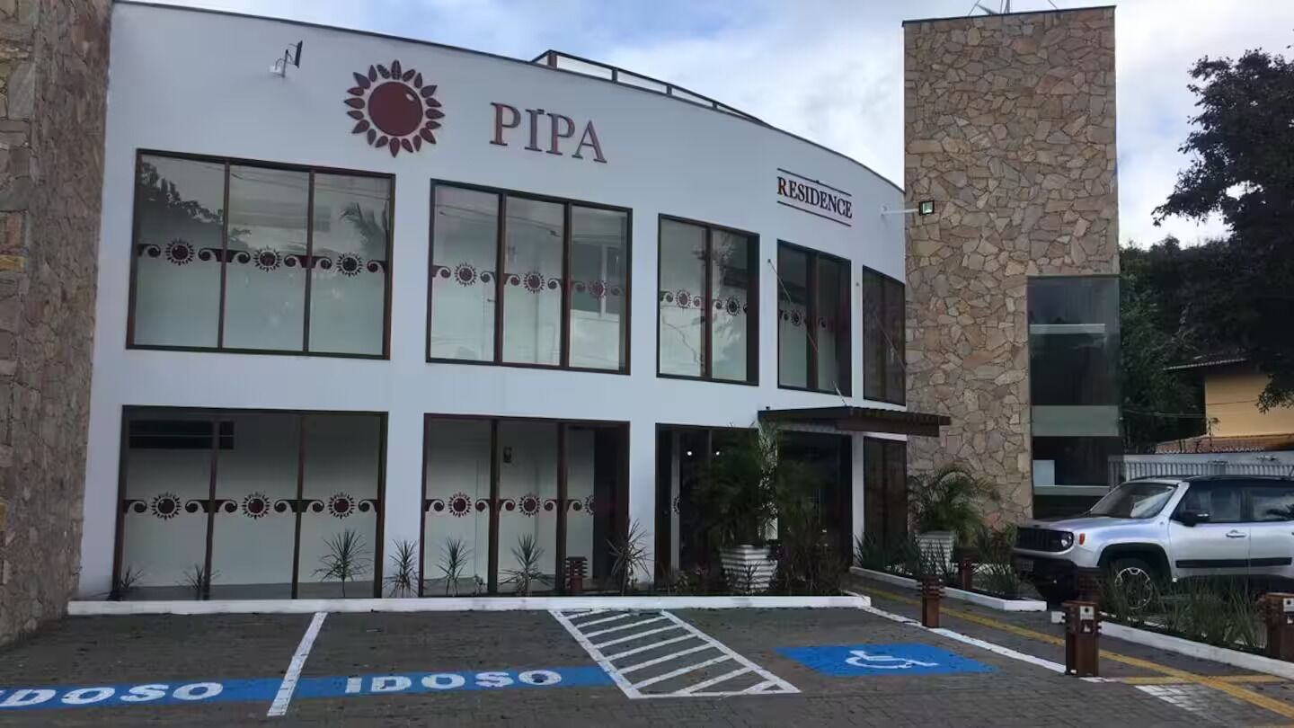 Um edifício com o logotipo PIPA, uma seção de residências e uma vaga de estacionamento para deficientes.