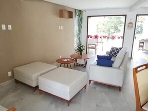 Una sala moderna con un sofá, un reposapiés y una pequeña mesa con una planta.
