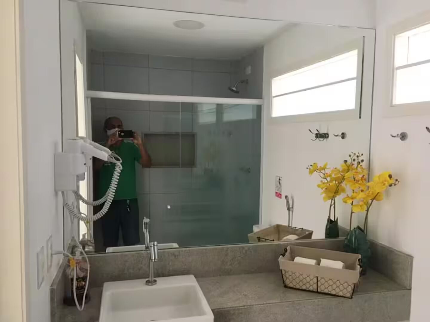 A bathroom with a sink, mirror, and a shower area.