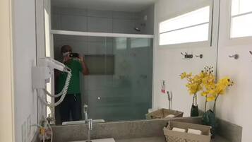 A bathroom with a sink, mirror, and a shower area.