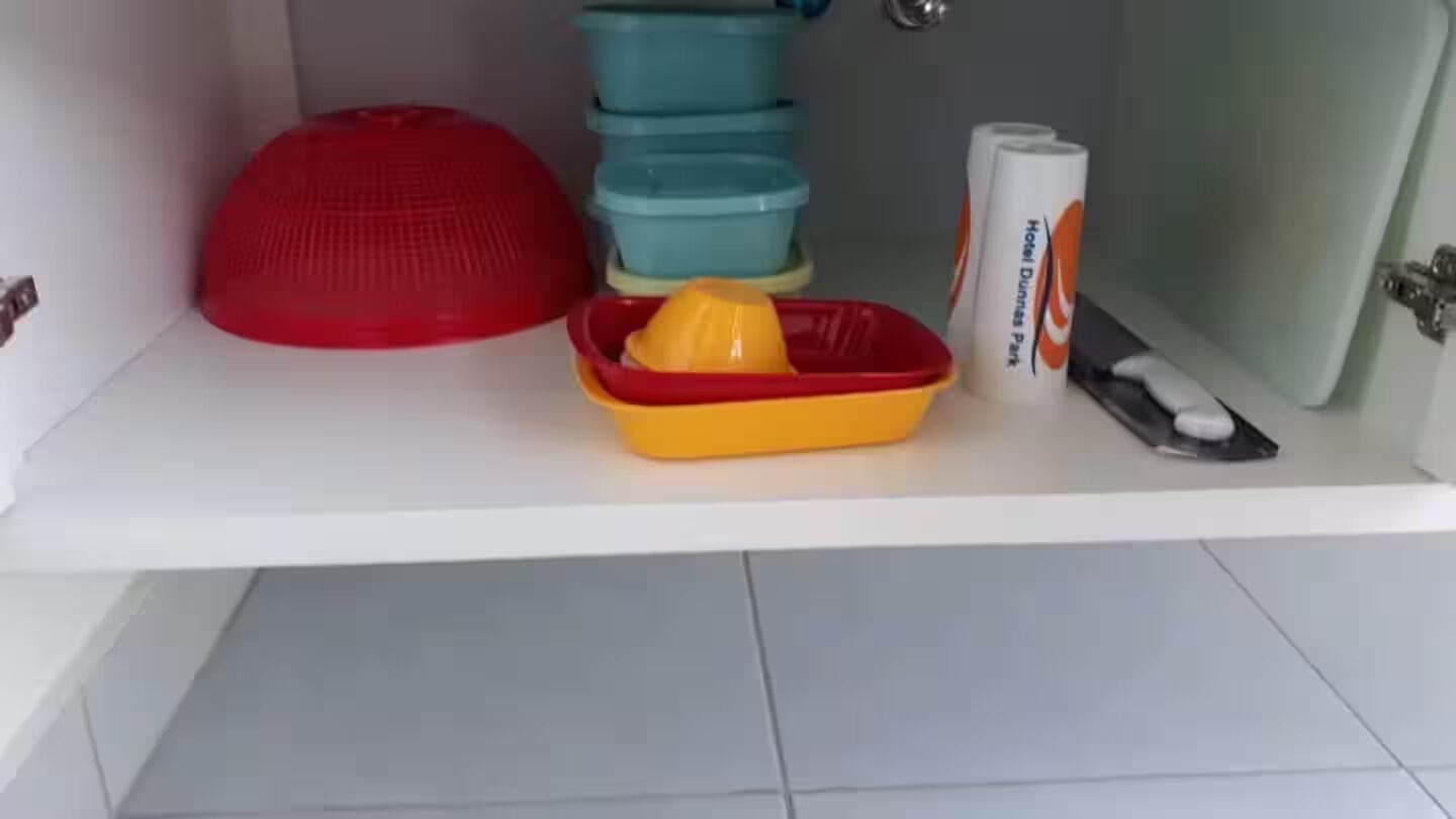 Una repisa de baño con un objeto rojo, un recipiente amarillo y un rollo de material promocional del hotel.