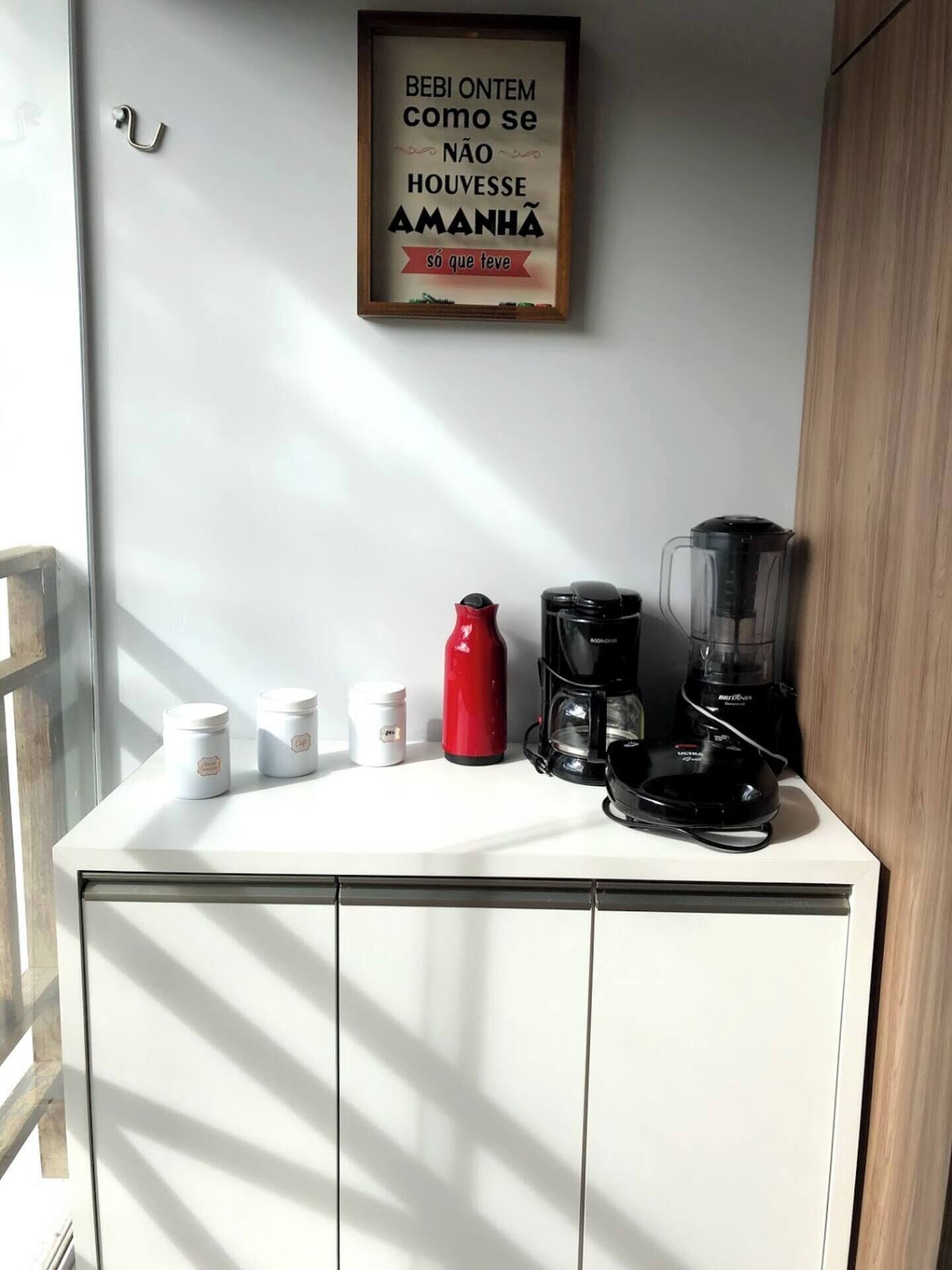 Un comptoir de cuisine avec une machine à café, une bouteille d’eau rouge et un mixeur.
