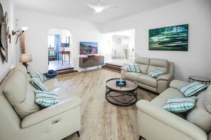 Een moderne woonkamer met een zithoek, een salontafel en een televisie.