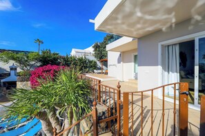 Une villa moderne dotée d’un balcon, d’une piscine et d’une végétation luxuriante.