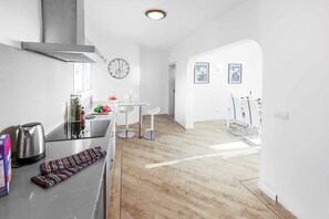 A modern kitchen with a stainless steel kettle, a clock, and a dining area with a table and chairs. - Villa Cilla - Four Bedroom Villa, Sleeps 8 (Puerto del Carmen)