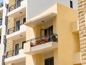 Un edifici de diverses plantes amb balcons, façana de pedra i teulada plana.
