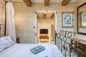 A hotel room with a bed, a TV, a wooden ceiling, and a staircase. - Charm Suite Valletta (Valletta)