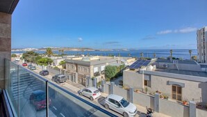 A residential area with a view of the sea, parked cars, and buildings with solar panels. - Modern Apartment with Sea View Qawra (St. Paul`s Bay)