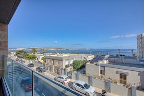 Ein Wohngebiet mit Blick auf das Meer, parkenden Autos und Gebäuden mit Solaranlagen.