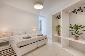 Ein zeitgemäßes Schlafzimmer mit einem Bett, Nachttischen, einer Hängelampe und zwei Blumentöpfen.