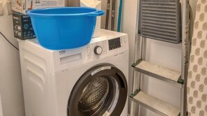 A laundry area with a washing machine, a drying rack, and a blue basin on top. - Modern Apartment with Sea View Qawra (St. Paul`s Bay)