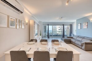Ein moderner Essbereich mit einem Tisch für vier Personen, einer Couch und einem Balkon mit Sitzgelegenheit im Freien.