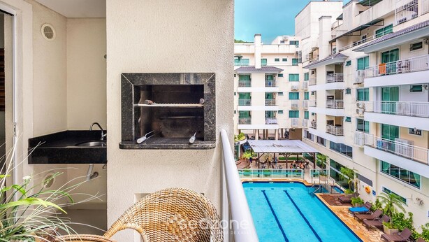 A balcony with a black sink, a small shelf, and a wicker chair. - Beautiful Apt in a Cond. With Heated Pools Sbh0233 (Bombinhas)