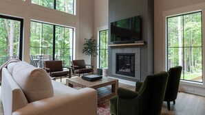 Amplia sala de estar con chimenea, ventanas grandes y televisor.