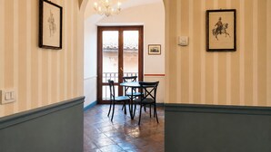 A hallway with striped wallpaper, a chandelier, framed pictures, and a view through a door. - Old Town Elegant Apartment in Anguillara (Anguillara Sabazia)