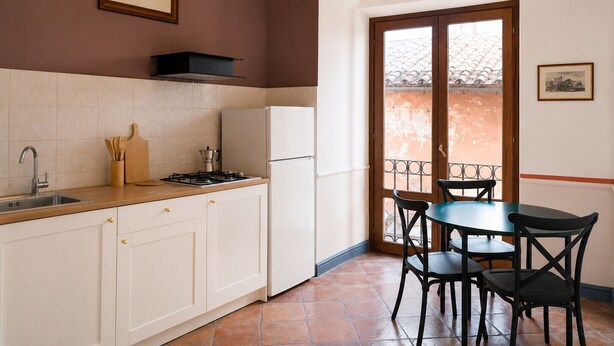 A kitchen with white cabinets, a gas stove, and a refrigerator. There is a dining table with chairs and a chandelier. - Old Town Elegant Apartment in Anguillara (Anguillara Sabazia)