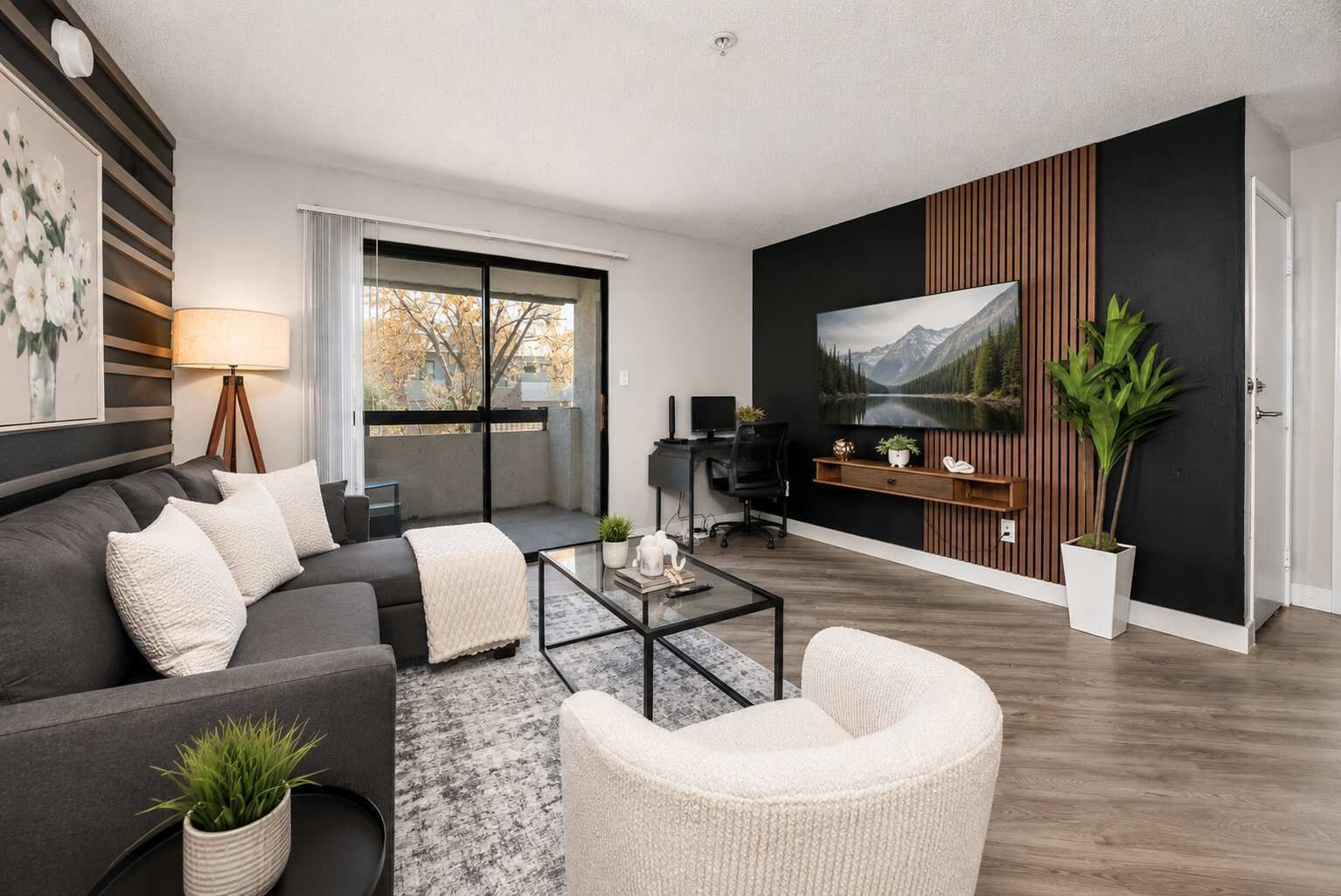 A modern living room with a sofa, armchair, coffee table, and a painting on the wall.