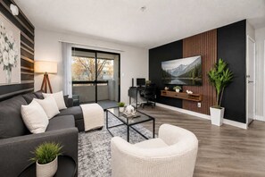 A modern living room with a sofa, armchair, coffee table, and a painting on the wall. - Modern Tempe Retreat Near ASU Pool, Gym, Pet-Friendly, Parking (Tempe)