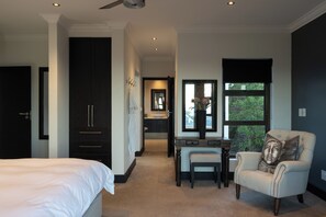 A bedroom with a bed, a desk, a chair, and a window with a view. - Luxury Coastal Retreat (Knysna)