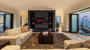 Uma sala de estar moderna com televisão de tela plana, um sofá, uma mesa de centro e uma janela grande com vista.