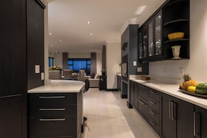A modern kitchen with dark cabinetry, a central island, and a dining area in the background.