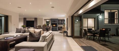A modern living room with a fireplace, a dining area, and a view of the outdoors.