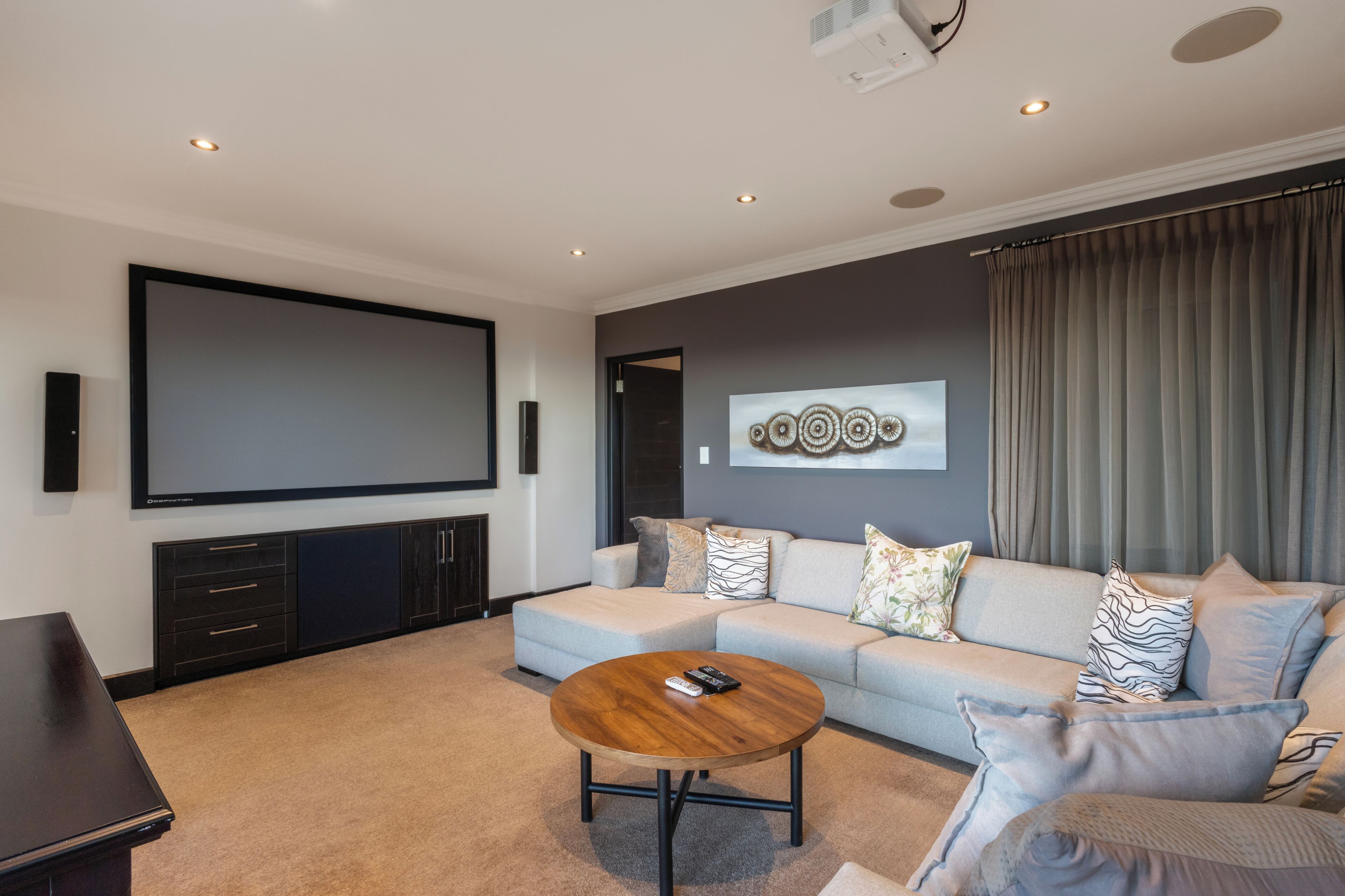Ein modernes Wohnzimmer mit Flachbildfernseher, einer Couch, einem Couchtisch und einem Wandbild.