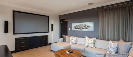 A modern living room with a flat-screen TV, a sofa, a coffee table, and a wall-mounted artwork.