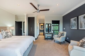 Une chambre à coucher avec un grand lit, un bureau, une chaise et un ventilateur de plafond.