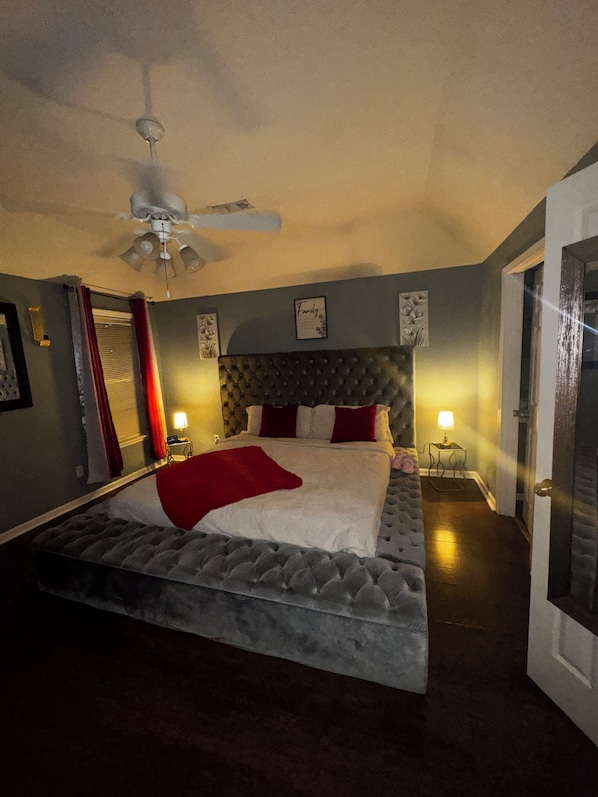 Une chambre à coucher avec un lit, un ventilateur de plafond, une table de chevet avec une lampe et une porte.