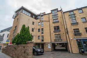 A multi-story building with a stone facade, multiple windows, and a car parked in front. - Stylish Apartment | Minutes from the Royal Mile - Pass the Keys (Edinburgh)