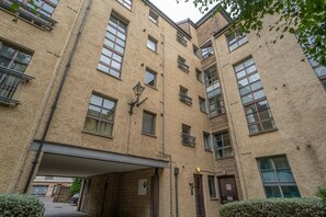 A multi-story building with a textured facade, multiple windows, and a covered entrance area. - Stylish Apartment | Minutes from the Royal Mile - Pass the Keys (Edinburgh)