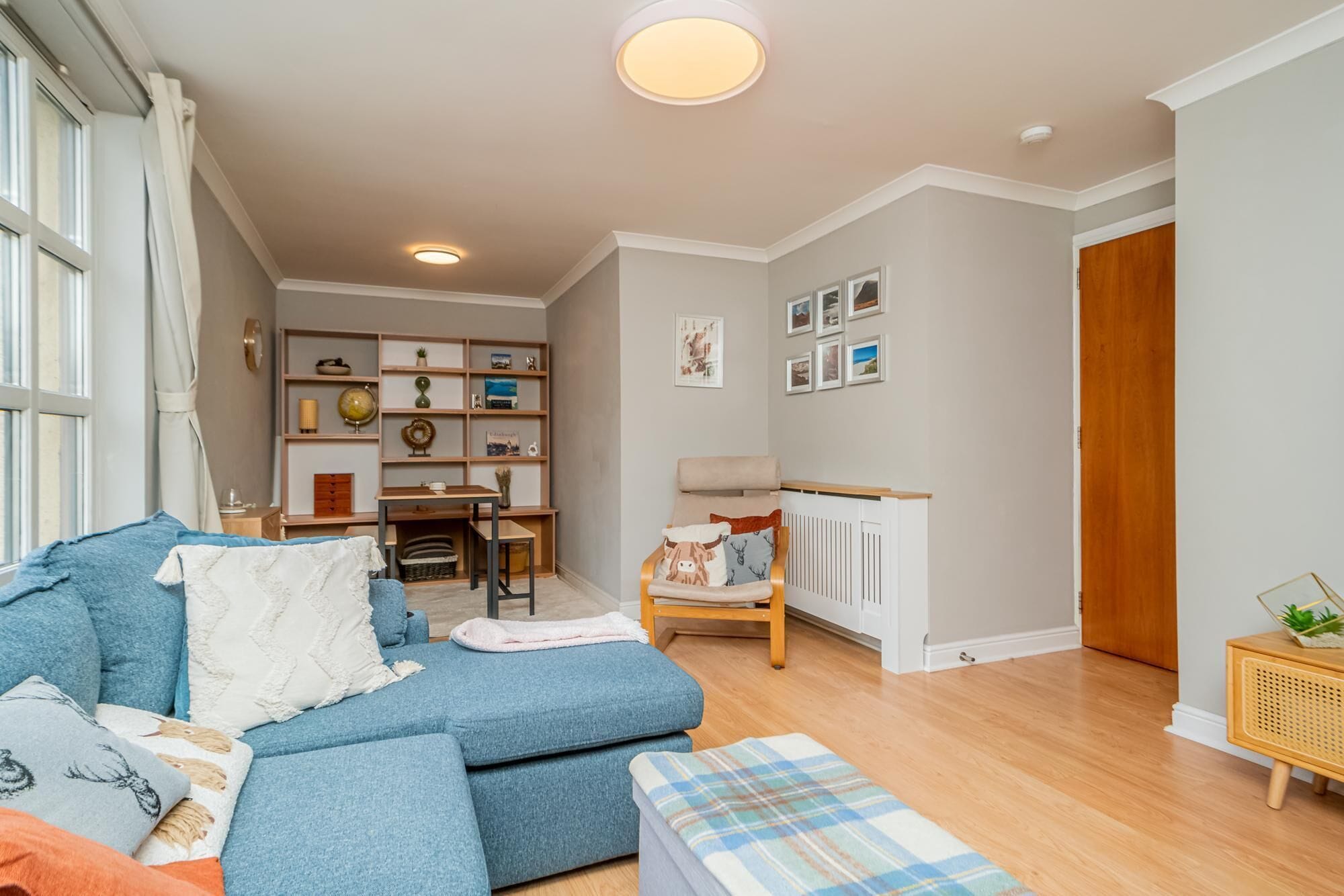 A living room with a sofa, a small table, a bookshelf, and a radiator.