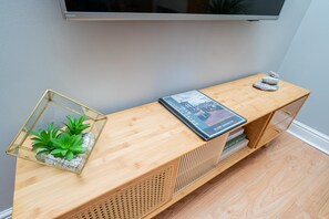 A wooden console table with a spiral-bound guest handbook, a glass terrarium with green plants, and a stack of books. - Stylish Apartment | Minutes from the Royal Mile - Pass the Keys (Edinburgh)