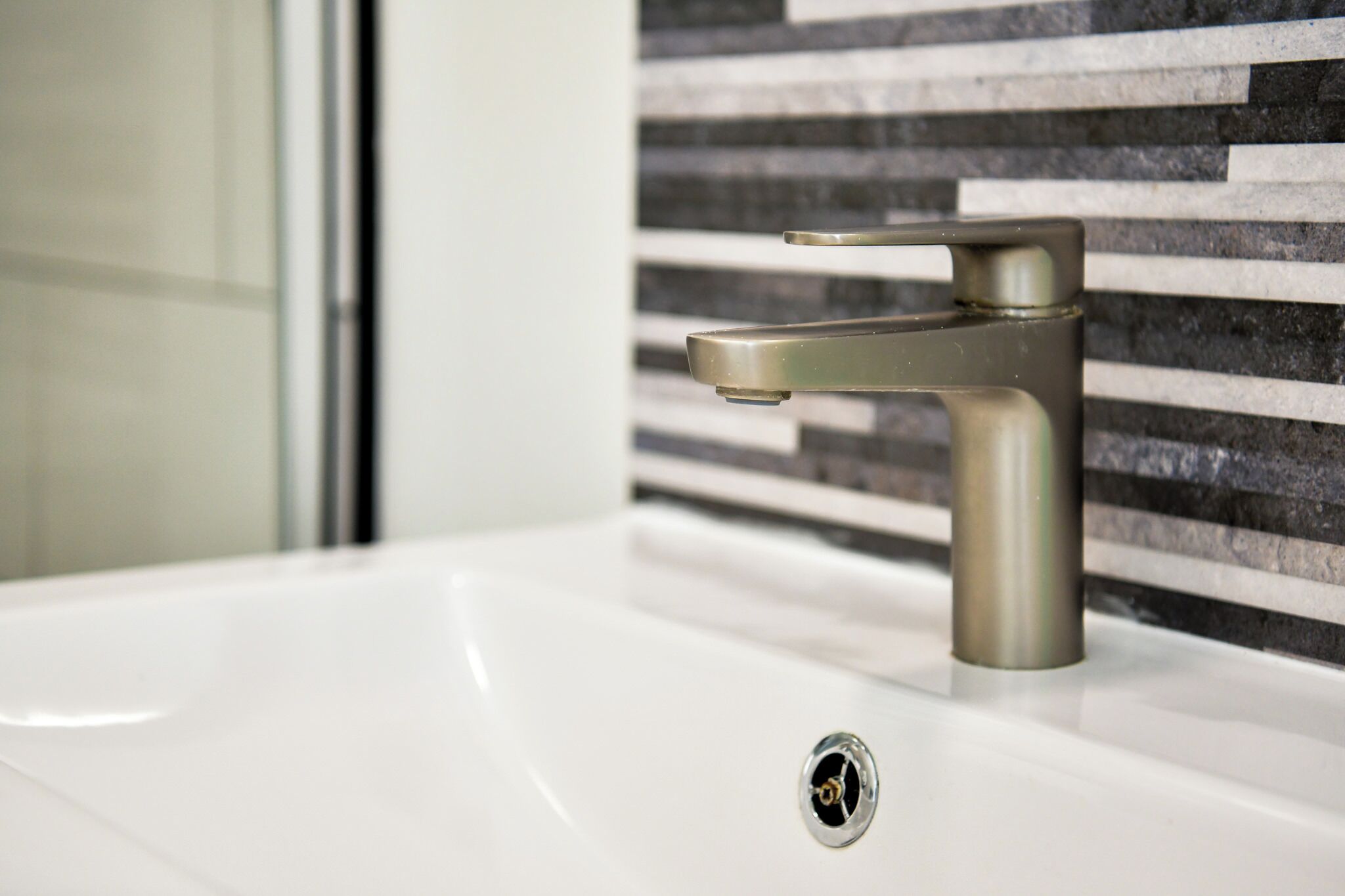Un lavamanos de baño con una llave moderna y desagüe.