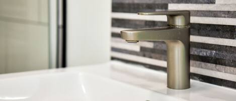 Un lavamanos de baño con una llave moderna y desagüe.