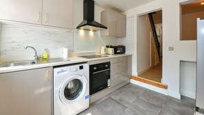 Una cucina moderna con lavatrice integrata, forno a microonde e fornello.