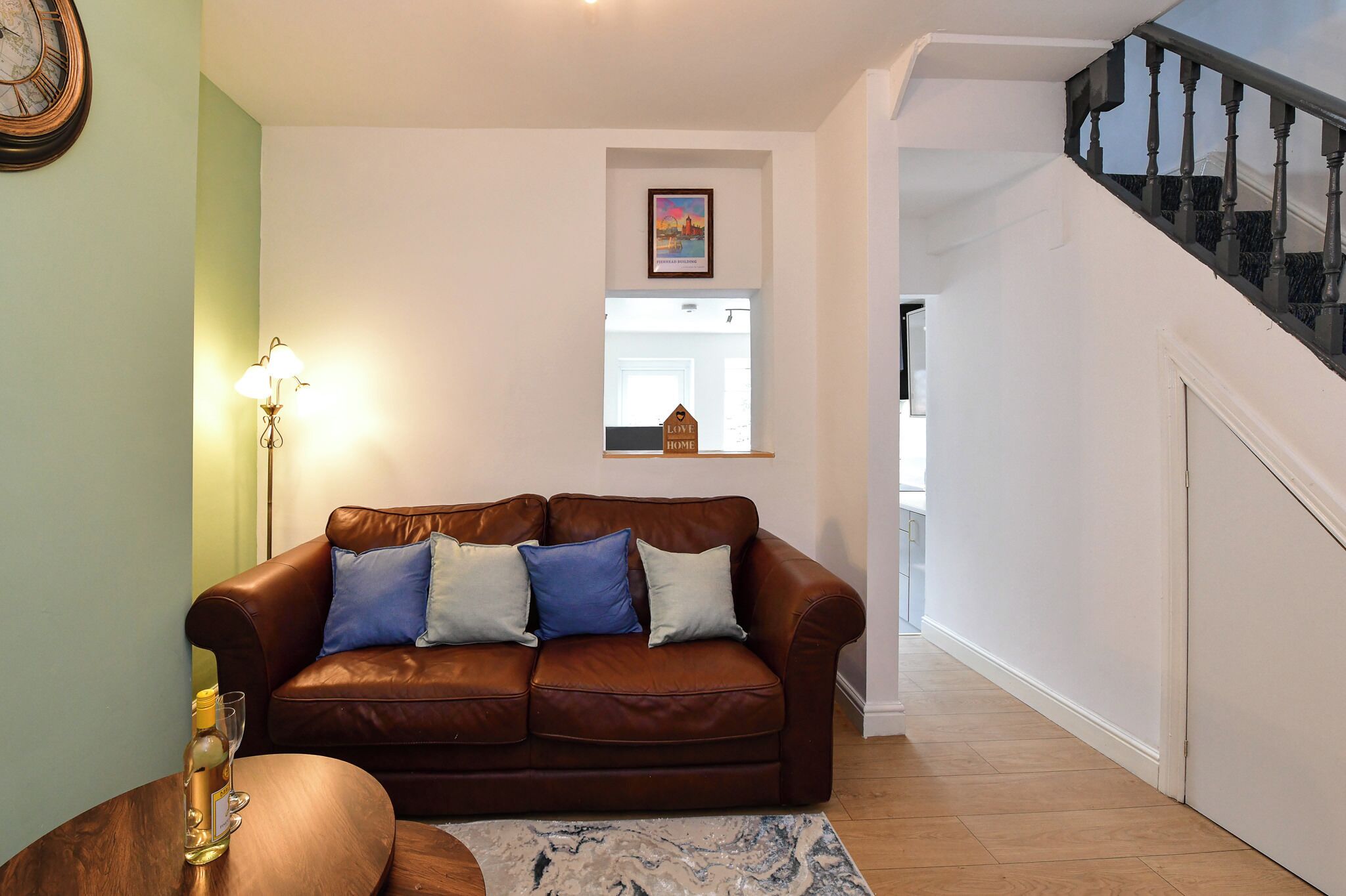 A living room with a brown leather sofa, a lamp, and a framed picture on the wall.