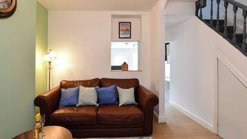 A living room with a brown leather sofa, a lamp, and a framed picture on the wall.