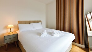Una camera d'albergo con un letto, un comodino con una lampada e una parete rivestita in legno.